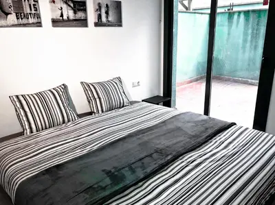 a bed with striped pillows in a bedroom with a window at Urban Manesa city center apartment with private patio in Manresa