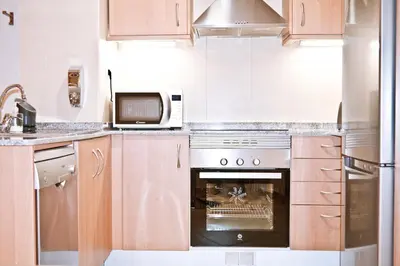 a kitchen with a stove and a microwave at Urban Manesa city center apartment with private patio in Manresa