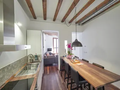 a kitchen with a long wooden counter top in a room at BarcelonaForRent Alessandra Ramblas in Barcelona