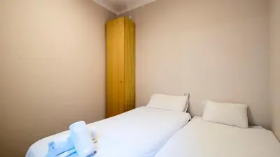 two beds in a small room with white sheets at Acogedor apartamento de 2 dormitorios in Barcelona