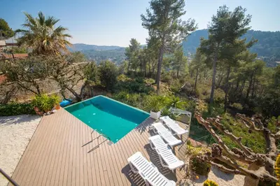 a swimming pool on a wooden deck with white chairs at Catalunya Casas Infinity pool and views 20min to Barcelona in Torrelles de Llobregat
