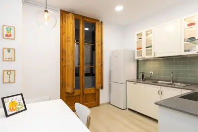 a kitchen with white cabinets and a white refrigerator at Modernist Family Apartment by PriorityVillas in Barcelona