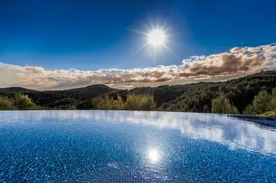 a large swimming pool with the sun in the background at Casa Nova Estate in Sitges