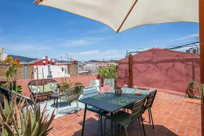a patio with a table and chairs and an umbrella at Glam Penthouse Barcelona in Barcelona