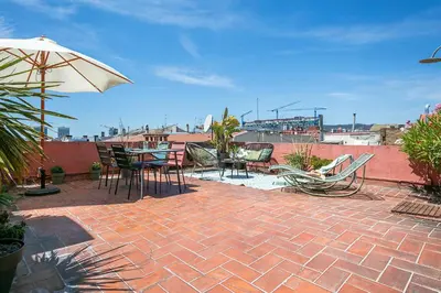 a patio with a table and chairs and an umbrella at Glam Penthouse Barcelona in Barcelona