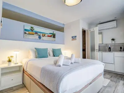 a bedroom with a large white bed and a kitchen at Blue Serenity by Hello Homes Sitges in Sitges