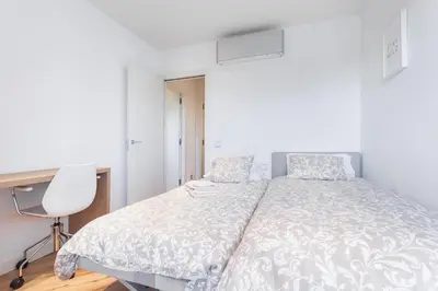 a bedroom with a bed and a desk and a chair at HHBCN Beach Apartment Gava #2 in Gavà