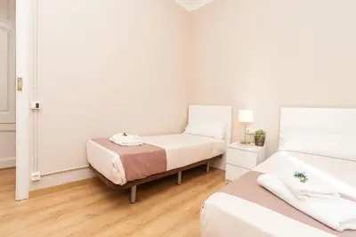 a white bedroom with two beds and a lamp at Housalia Sagrada Familia in Barcelona