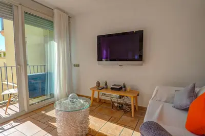 a living room with a couch and a tv on the wall at La Marina Sea Front by Hello Homes Sitges in Sitges