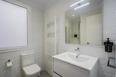 a white bathroom with a toilet and a sink at Ola Living Diagonal II Apartments in Barcelona