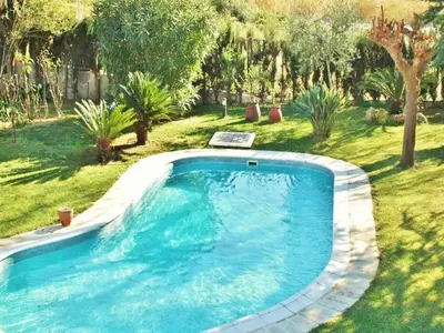 a large blue swimming pool in a yard with trees at Villa in Sant Pol near Crystal Beach in San Pol de Mar