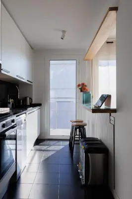 a kitchen with white cabinets and a large window at Gran Apartmento Playa Badalona in Badalona