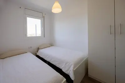 two beds in a small room with a window at Gran Apartmento Playa Badalona in Badalona