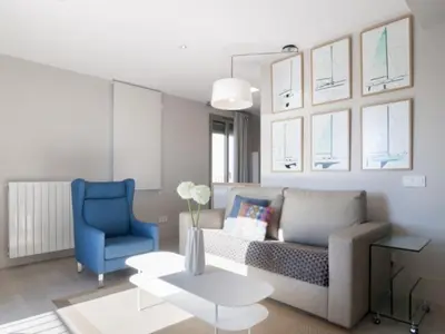 a living room with a couch and a blue chair at Kronos on the Beach Attic Suite in Barcelona