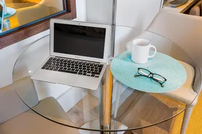 a laptop on a glass table with a cup of coffee at Kronos on the Beach suite 3 in Barcelona
