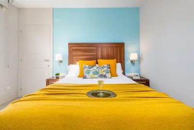 a bed with a yellow blanket with a wine glass on it at Kronos on the Beach suite 3 in Barcelona
