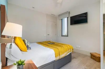 a bedroom with a bed with a yellow blanket at Kronos on the Beach suite 3 in Barcelona
