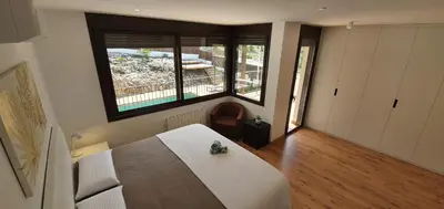 a room with a bed and a table and two windows at Villa Vicente in Canyelles