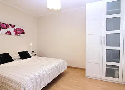 a white bedroom with a bed and a sliding door at MUNNE - Spacious apartments next to FC Barcelona in Barcelona