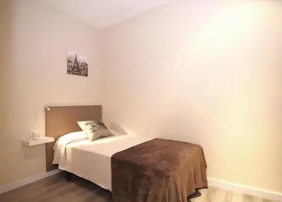 a small bedroom with a bed and a lamp at MUNNE - Spacious apartments next to FC Barcelona in Barcelona