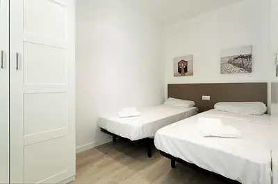 two beds in a room with white walls and wooden floors at MIQUEL ANGEL - Apartments & one with private terrace in Barcelona