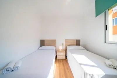 two twin beds in a room with a window at HomeHolidaysRentals Moana in Calella