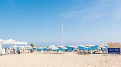 a beach with umbrellas and chairs and the ocean at HomeHolidaysRentals Moana in Calella