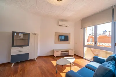 a living room with a blue couch and a tv at HomeHolidaysRentals Elodie in Calella