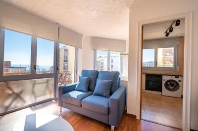 a living room with a blue chair and some windows at HomeHolidaysRentals Elodie in Calella