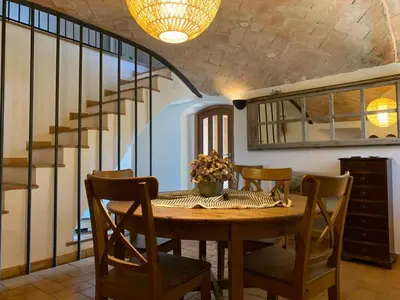 a dining room with a table and a staircase at Cal Secretari in Rellinars