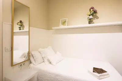 a bedroom with a white bed and a mirror at Chic Gran Via Apartment in Barcelona