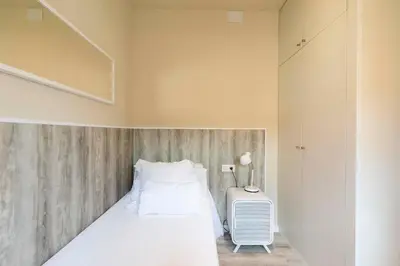 a small bedroom with a bed and a table at Chic Gran Via Apartment in Barcelona