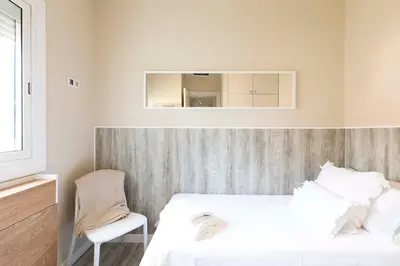 a bedroom with two beds and a chair and a mirror at Chic Gran Via Apartment in Barcelona