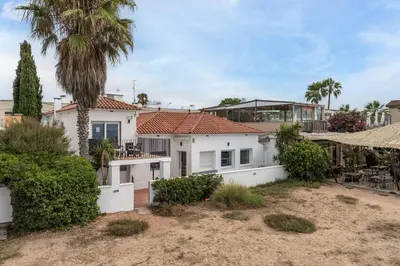a large white house with a palm tree at Beach Villa Cristina by HHBCN in Castelldefels