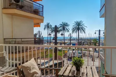 a balcony with a view of a beach and palm trees at La Gioia 1 by Hello Homes Sitges in Sitges