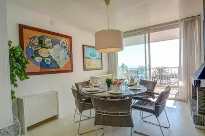 a dining room with a table and chairs and a painting at La Gioia 2 by Hello Homes Sitges in Sitges