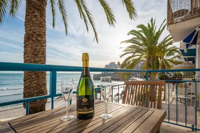a bottle of wine sitting on a wooden table with wine glasses at InSitges Sant Sebastia's Beach in Sitges