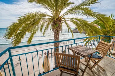 a balcony with a table and a palm tree on the beach at InSitges Sant Sebastia's Beach in Sitges