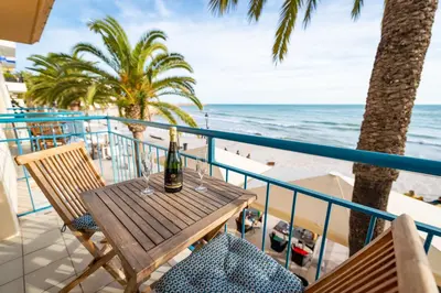 a table with a bottle of wine on a balcony overlooking the beach at InSitges Sant Sebastia's Beach in Sitges