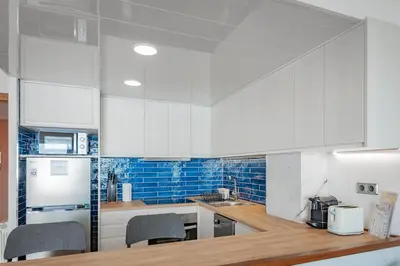 a kitchen with white cabinets and blue tiles at InSitges Sant Sebastia's Beach in Sitges