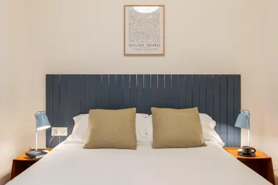 a bedroom with a large bed with a blue headboard at Rafael Apartment by Olala Homes in Hospitalet de Llobregat