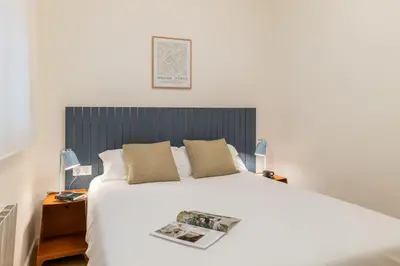 a bedroom with a white bed with a black headboard at Rafael Apartment by Olala Homes in Hospitalet de Llobregat