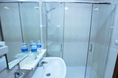 a bathroom with a shower and a sink with bottles of water at Hotel Tres Leones in Vilassar de Mar