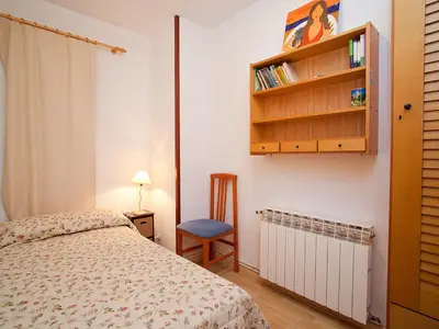 a bedroom with a bed and a chair and a book shelf at Apartment Edificio Blanqueries by Interhome in Calella