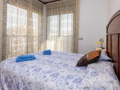 a bedroom with a bed with a blue comforter and two windows at Apartment Poblenou by Interhome in Barcelona