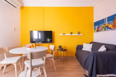 a living room with a table and a yellow wall at Sunny Apt Barcelona 22 in Barcelona