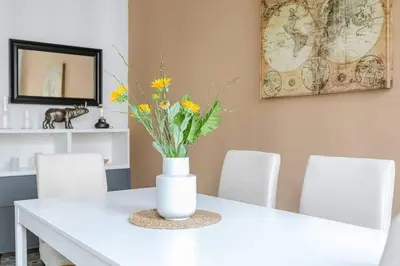 a white dining room table with a vase with flowers on it at Exquisite&historic Flat With Rooftop in Barcelona