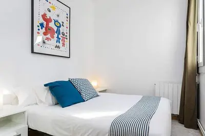 a bedroom with a white bed with a blue pillow at Vive Como Un Barcelons in Barcelona