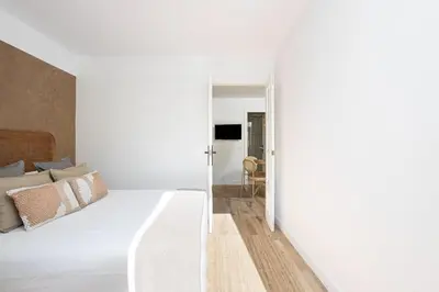 a bedroom with a large white bed and a hallway at Walk To Las Ramblas Sun-filled&cozy in Barcelona