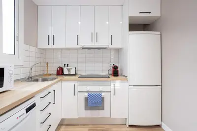 a white kitchen with white appliances and white cabinets at Walk To Las Ramblas Sun-filled&cozy in Barcelona